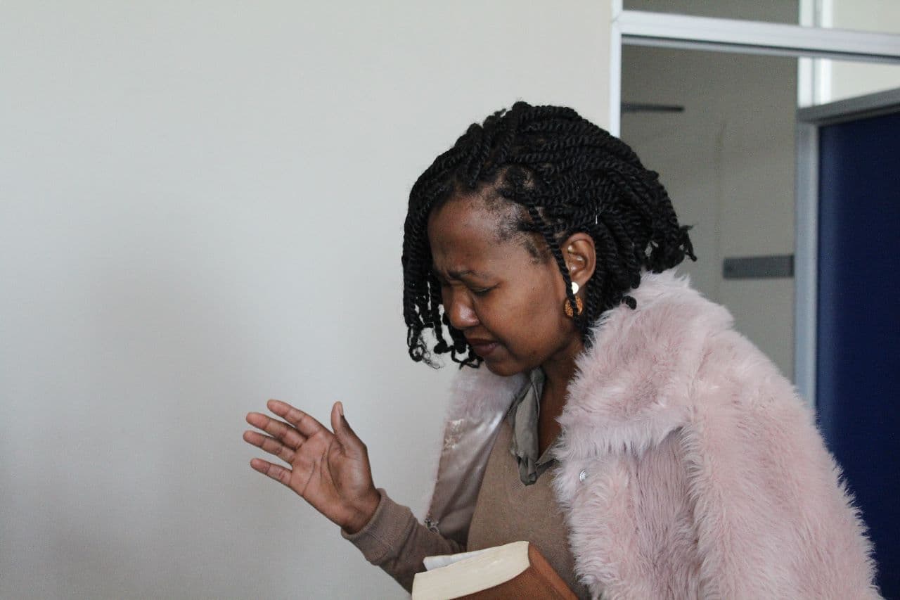 Apostle Light praying while holding the Bible.